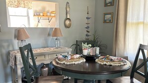 Un comedor con una mesa redonda, sillas, un tapete y un letrero que dice "Bon Appetit".