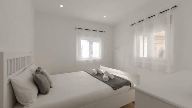 Une chambre moderne avec un grand lit, deux fenêtres ornées de rideaux légers et une table de chevet.