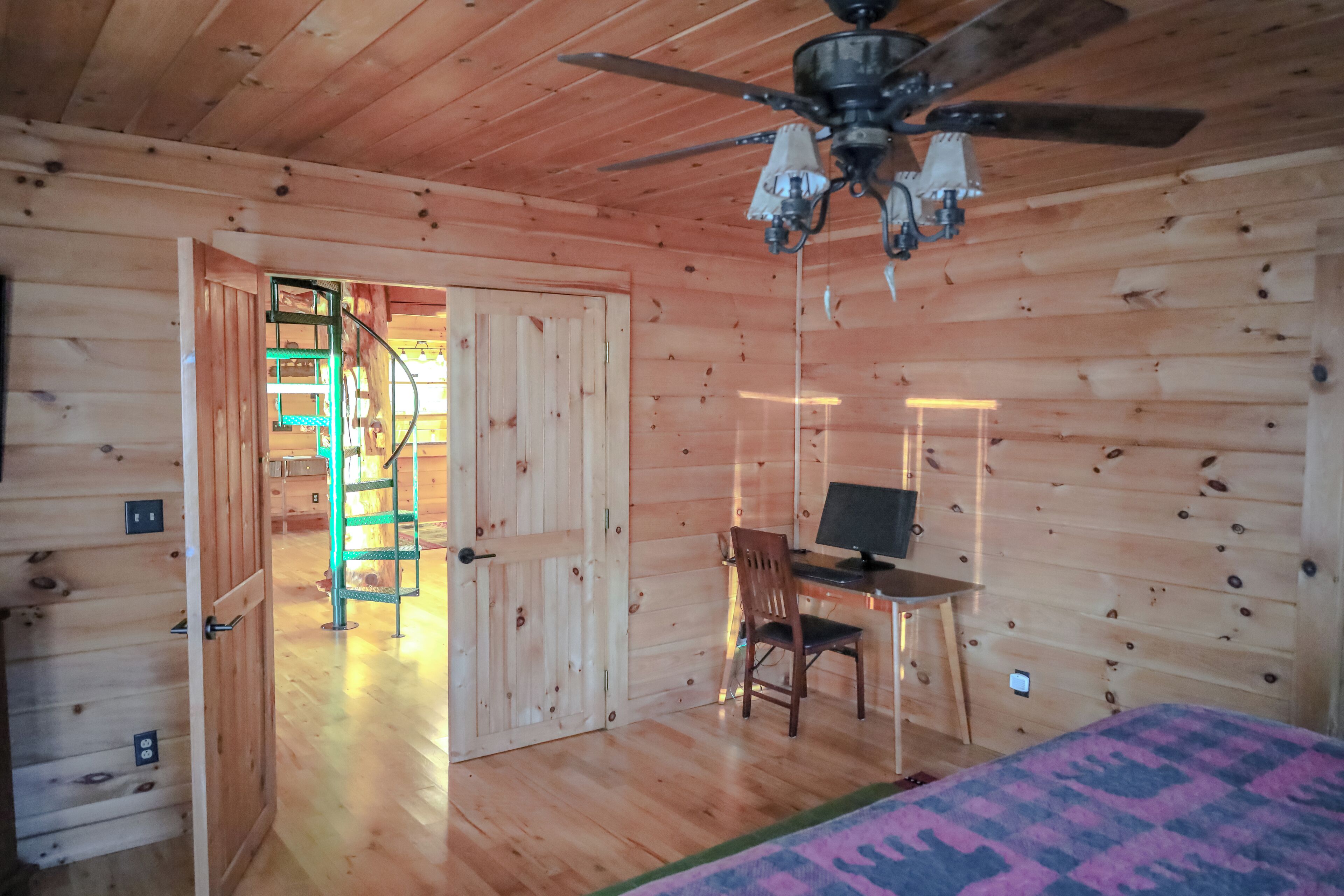 Interior de uma cabana de madeira com uma mesa, cadeira e cama.