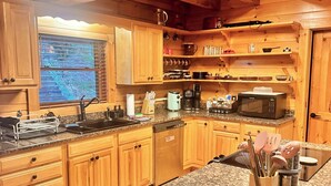 A wooden cabin-style kitchen with granite countertops, wooden cabinets, and a built-in microwave. - Skyline Lodge, beautiful lodge home with mountain and lake view (Butler)