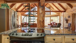 A kitchen with a central island, a stove, and wooden cabinetry. - Skyline Lodge, beautiful lodge home with mountain and lake view (Butler)