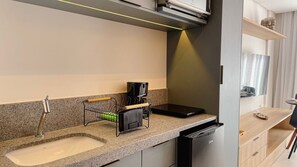Eine moderne Küche mit integriertem Geschirrspüler, einer Kaffeemaschine und einem Spülbecken.