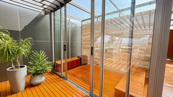 Un intérieur moderne avec une terrasse en bois, des portes vitrées et des plantes en pot.