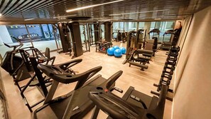 Una palestra con tapis roulant, macchinari per pesi e palle da ginnastica.
