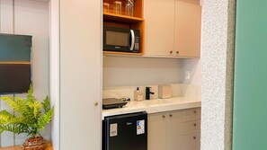 Une cuisine compacte équipée d’un four à micro-ondes, d’un petit réfrigérateur et d’un évier.