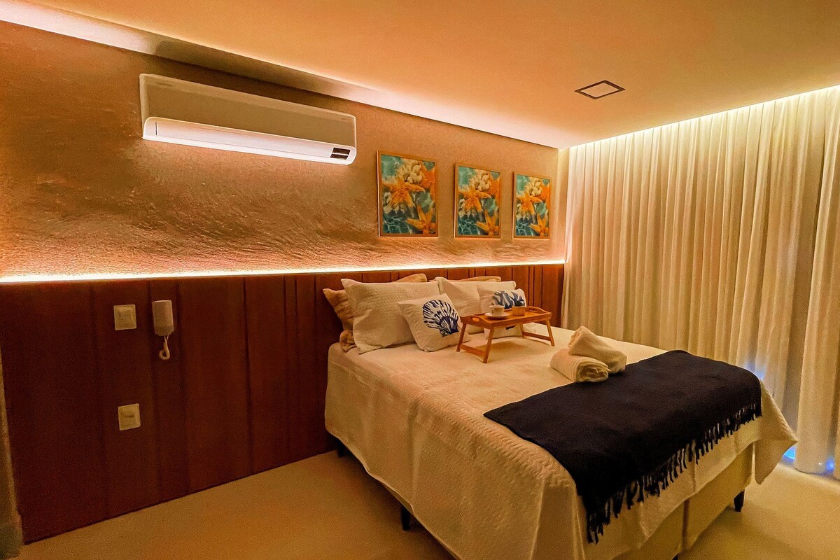 Une chambre d’hôtel équipée d’un lit, d’une table de chevet, d’un appareil de climatisation et d’une fenêtre avec des rideaux.