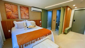Una camera d'albergo con un letto, un comodino e vista sul bagno.