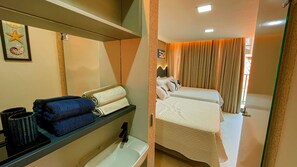 A hotel room with a bed, a sink, a mirror, and a shelf with towels and a mug. - Aquamaris Luxo - by Almare (João Pessoa)