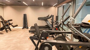 Ein Fitnessstudio mit verschiedenen Trainingsgeräten, darunter Laufbänder, Kraftgeräte und ein Squat-Rack.
