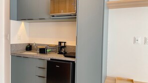 A compact kitchen with grey cabinets, a dishwasher, a coffee maker, and a small countertop. - Aquamaris Luxo - by Almare (João Pessoa)