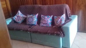 Ein saphirblaues Sofa mit einer braunen Decke und gemusterten Kissen vor einer Holzwand.