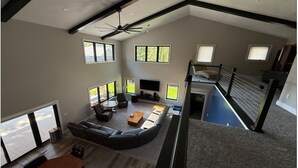Amplia sala de estar con un sofá modular grande, una mesa de centro y un televisor de pantalla plana. Varias ventanas ofrecen luz natural y vistas al exterior.