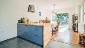 A modern kitchen with a central island, blue cabinets, and a dining area with wooden chairs and a table.