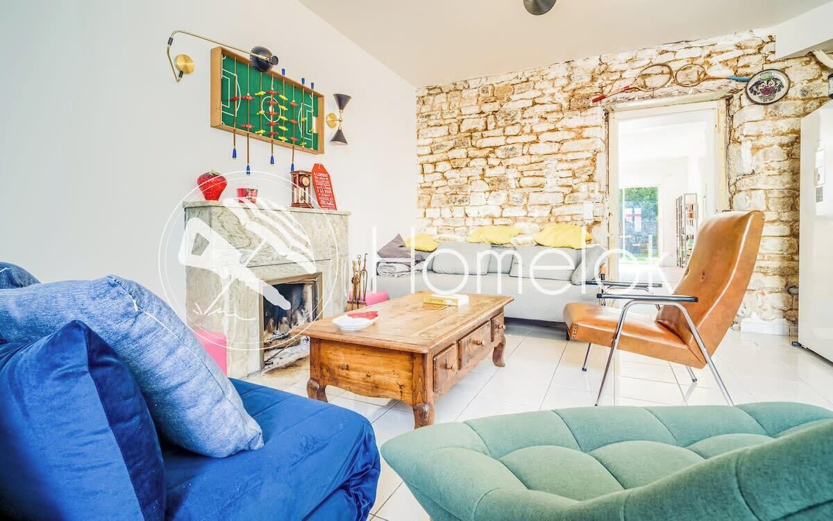 Una sala de estar con pared de piedra, una mesa de centro de madera, un sofá azul y un sillón verde.