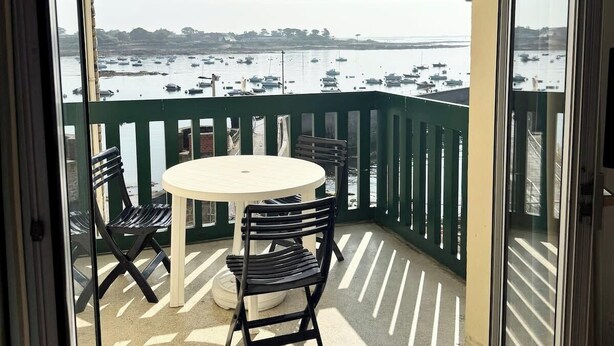 A balcony with a table and chairs, overlooking a marina with boats. - Appartement idéal face mer – Tout à pied (Ploemeur)