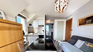 A compact living space with a dining area, kitchenette, and a sofa. - Appartement idéal face mer – Tout à pied (Ploemeur)