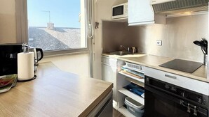 A compact kitchen with a window, a microwave, a sink, and a dishwasher. - Appartement idéal face mer – Tout à pied (Ploemeur)