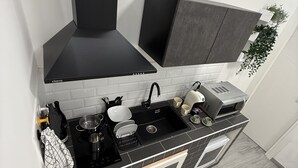 A modern kitchen with a black stove, white sink, and grey cabinets.