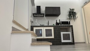 A modern kitchen with a built-in stove, microwave, and cabinets. There is a staircase leading to another level.