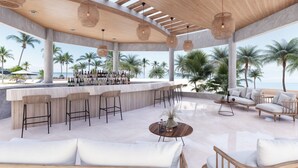 A spacious outdoor lounge area with a bar, seating, and a view of the beach.