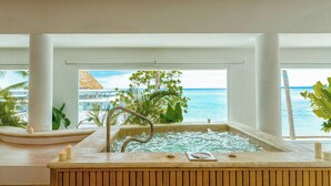 A hot tub with a view of the ocean and a thatched roof structure.