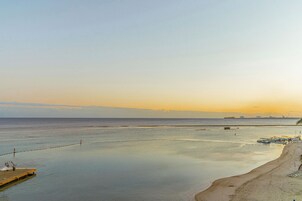 A beach with a wooden pier and boats, a sandy shore, and a calm sea.