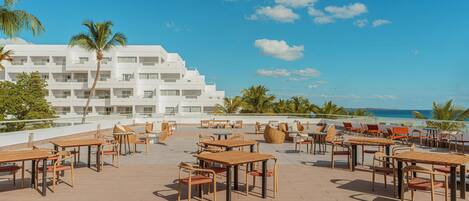 A rooftop terrace with outdoor seating and a view of the ocean.
