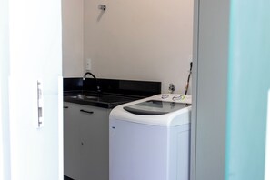 A compact kitchen with a sink, a stove, and a washing machine.