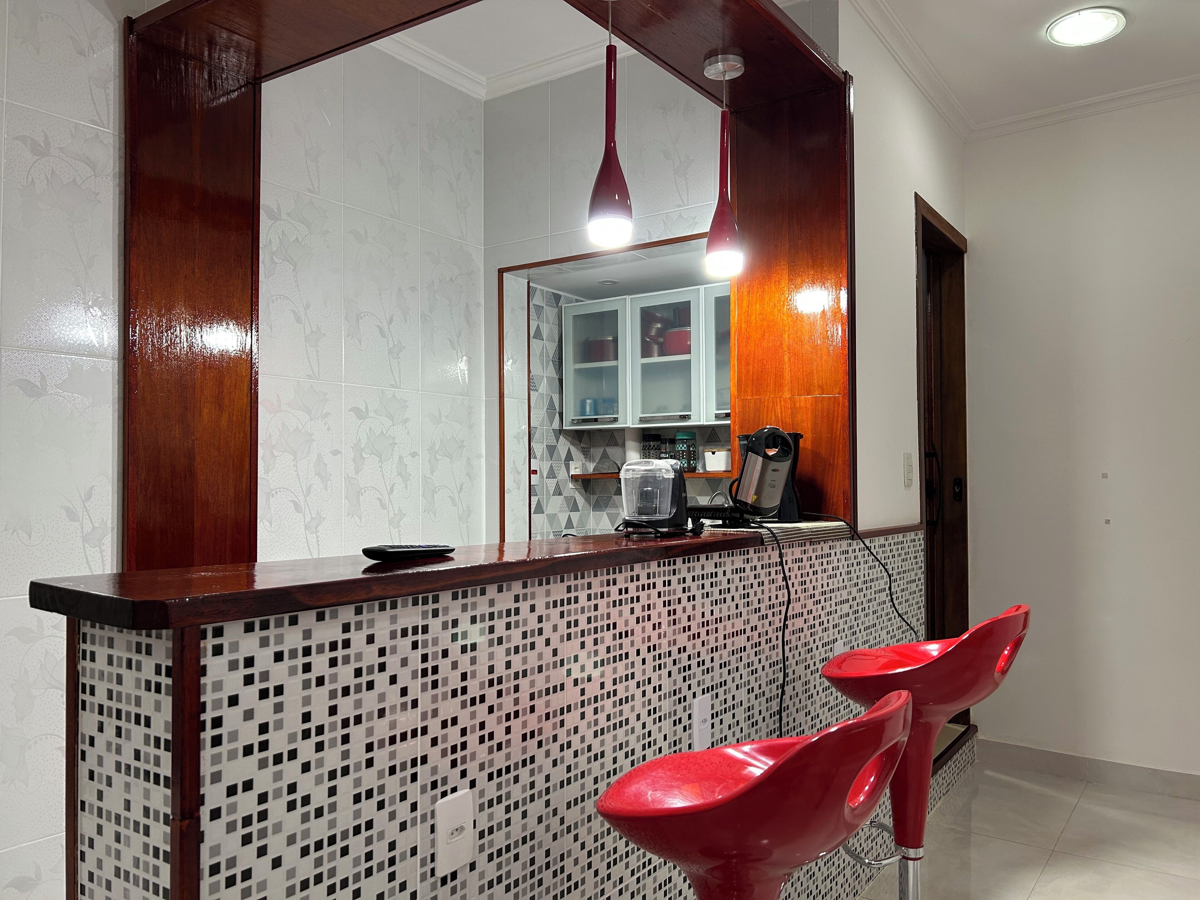 A kitchen with a tiled backsplash, a wooden counter, and two red bar stools.