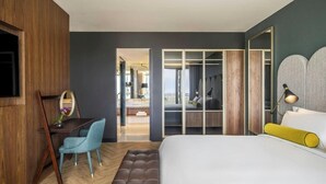 Camera d'albergo moderna con un letto, una scrivania con sedia, uno specchio e un armadio.