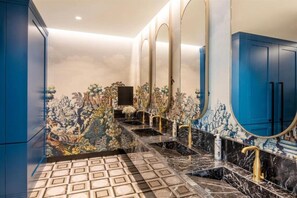 A bathroom with a marble floor, multiple sinks, and blue cabinets.