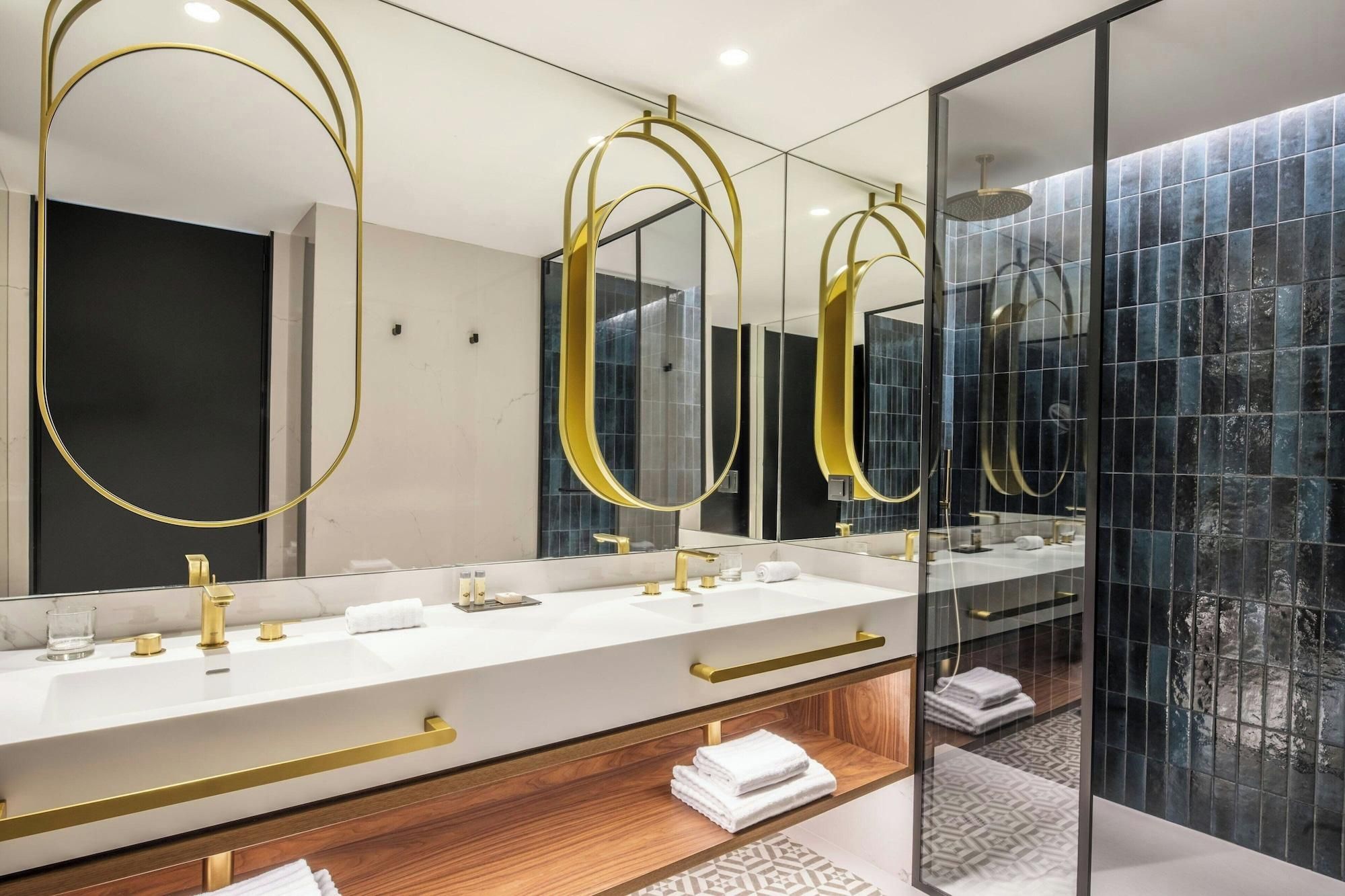 A modern bathroom with dual sinks, gold fixtures, and a large mirror with gold accents.