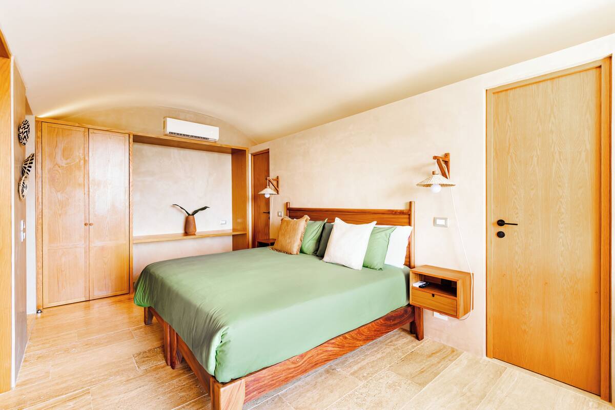A bedroom with a wooden bed, a bedside table, a wardrobe, and a door.