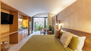 Una habitación de hotel con cama, televisión, kitchenette y vistas al jardín.