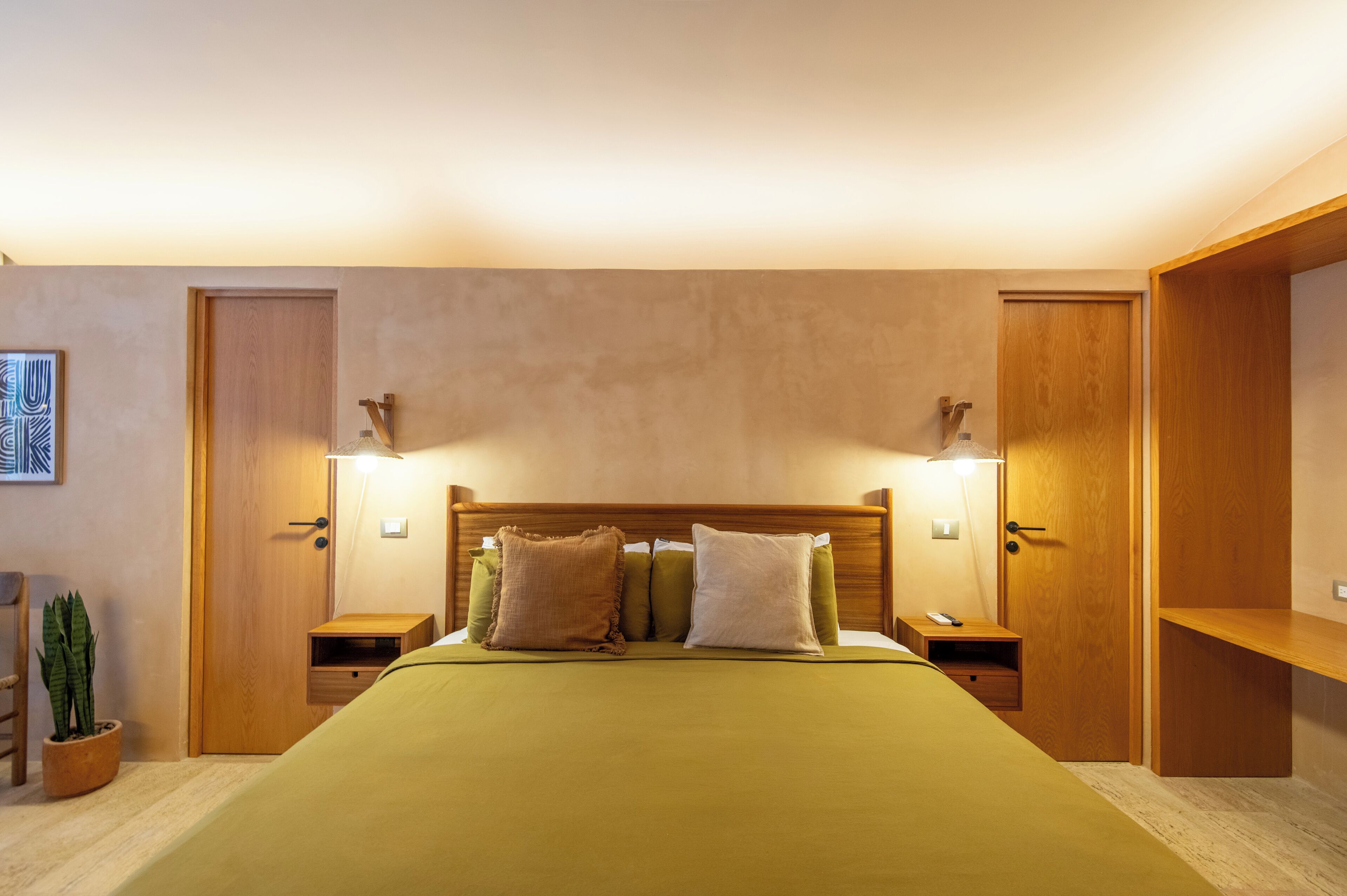 A neatly arranged bedroom with a bed, bedside tables, a nightstand, a potted plant, and a wooden wardrobe.
