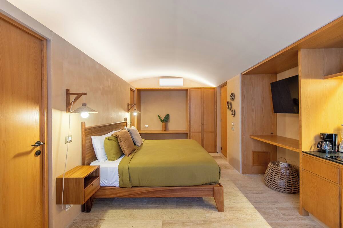 A compact bedroom with a bed, bedside table, and built-in TV shelf.