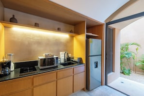 Une cuisine moderne avec des meubles en bois, un four à micro-ondes encastré, une machine à café et un réfrigérateur.