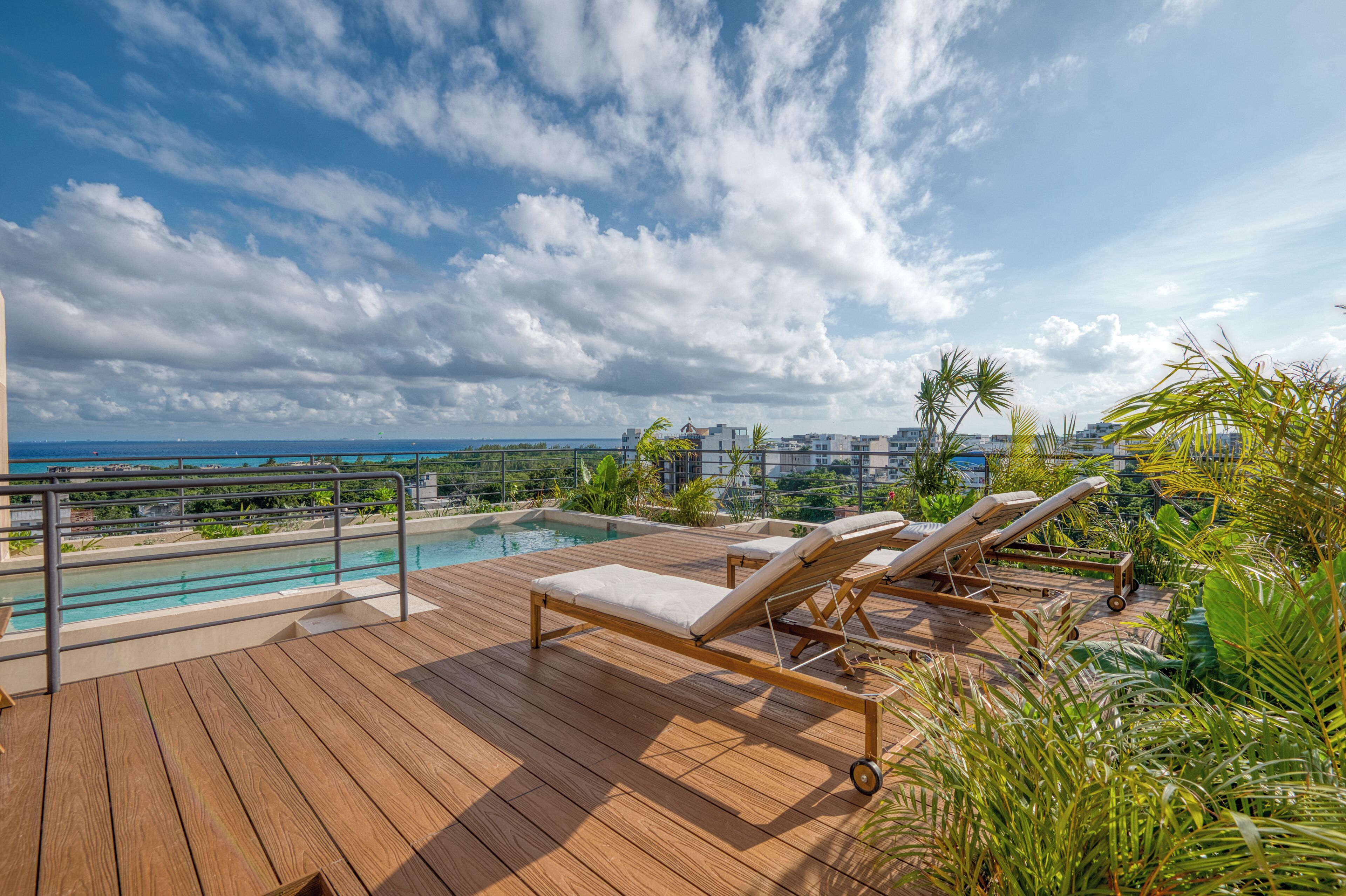 A rooftop pool area with lounge chairs and a view of the cityscape.
