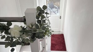 A staircase with a red carpet, white walls, a framed picture, and a window with a view. - The Chelsea Ambassadorial Executive Penthouse (London)