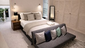 A bedroom with a bed, bedside tables, a bench, a wardrobe, and a mirror. - The Chelsea Ambassadorial Executive Penthouse (London)