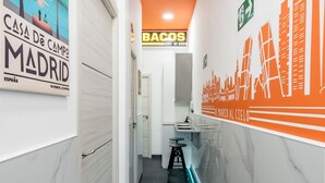 A hotel corridor with a bathroom featuring a sink and a mirror, and a bar area with stools. - Charming Madrid Las Rosas, 2 habitaciones (Madrid)