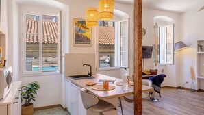 Una cocina moderna con una mesa de madera, un lavamanos y una ventana con vista a un tejado de tejas.