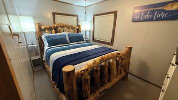 Een slaapkamer met een houten bedframe, een plafondventilator en een bord aan de muur.