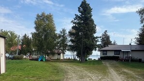 A gravel path leading to a row of cabins with a lake in the background. - Lake Life Landing Indian Lake Waterfront w/ Private Dock (Manistique)