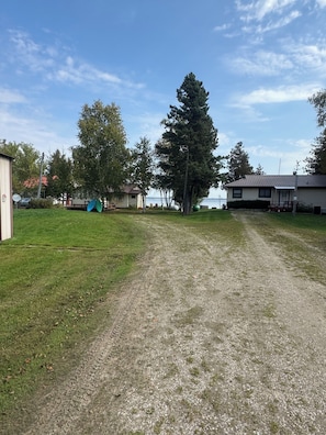 A gravel path leading to a row of cabins with a lake in the background. - Lake Life Landing Indian Lake Waterfront w/ Private Dock (Manistique)