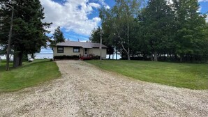 Een huis met een oprit van grind die uitkomt bij een voortuin.