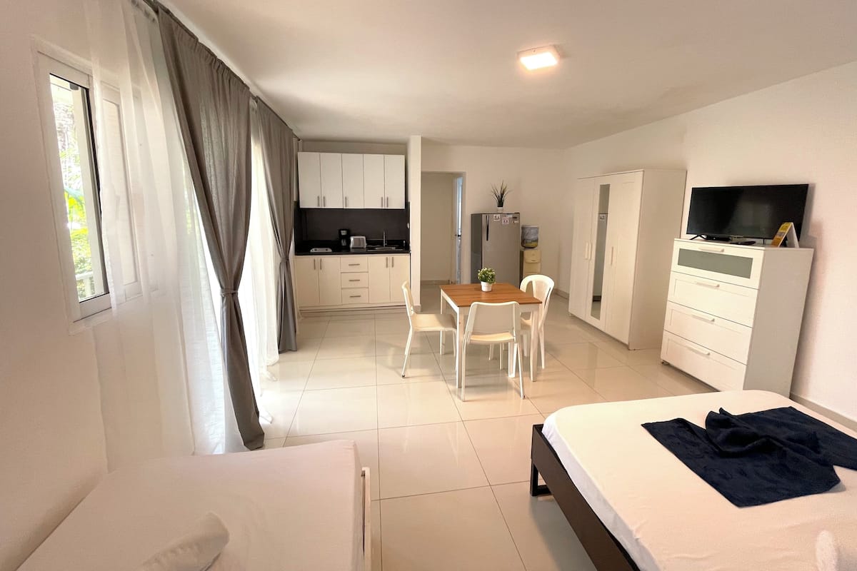 Habitación de hotel con cama, escritorio con silla, kitchenette y televisor en una cómoda.
