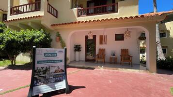 A hotel with a red-tiled roof, a spa treatment sign offering a 25% discount, and a reception area with wooden chairs and a hanging plant.