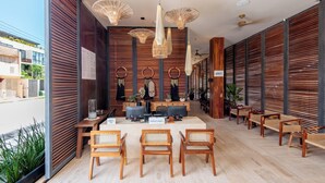 Un vestíbulo moderno de hotel con paneles de madera, un mostrador de recepción y varias zonas de estar.