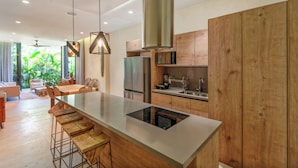 Una cocina moderna con una isla grande, armarios de madera y vista a un jardín exuberante.